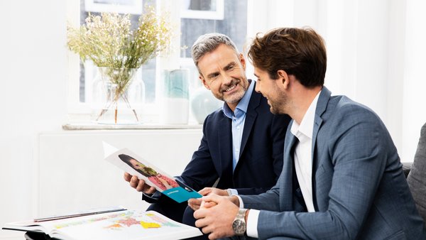 Двоє чоловіків сидять за столом і разом переглядають документи