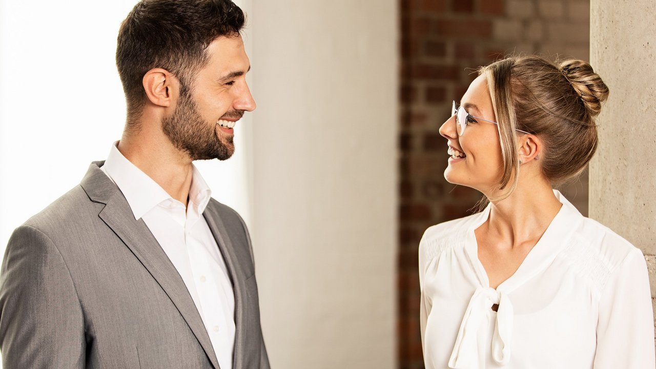 Чоловік і жінка розмовляють та посміхаються в приміщенні.