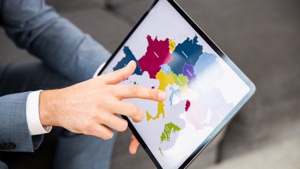 Людина вказує на цифрову карту, відображену на екрані планшета.