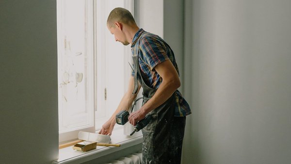 Чоловік ремонтує вікно - приватне страхування від професійної непрацездатності