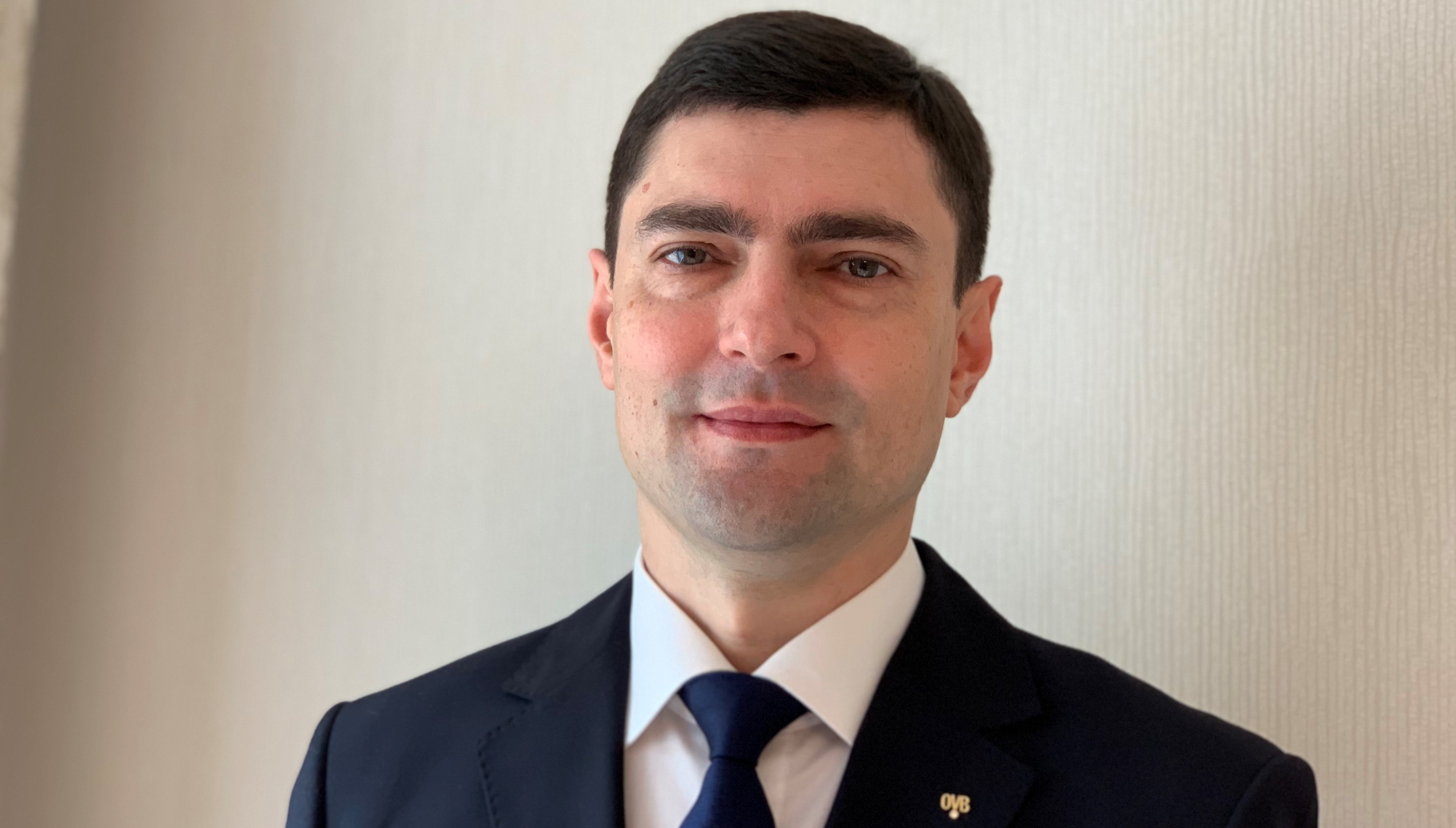 директор OVB Україна Чоловік у костюмі стоїть та посміхається в камеру.
