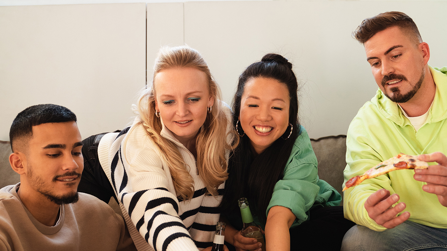 Що таке спільна квартира Четверо молодих людей сидять разом на дивані і сміються