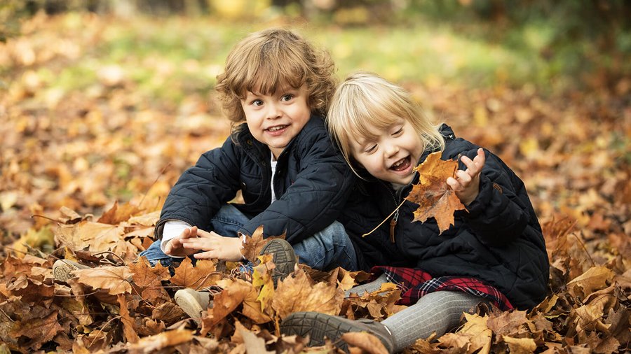 Дві дитини сидять у осінній листві