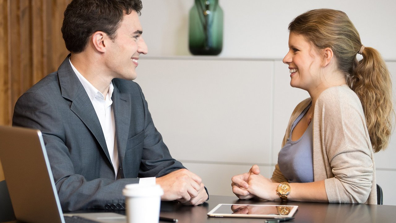 Чоловік і жінка сидять за столом та розмовляють під час ділової зустрічі.