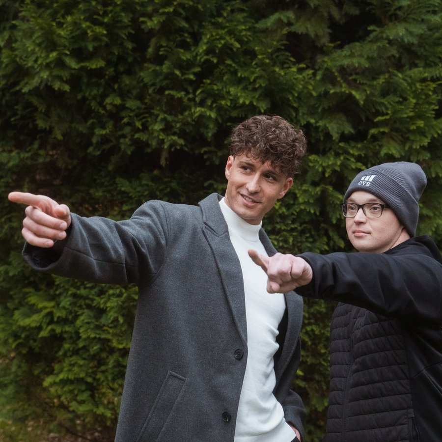 Дві людини стоять на вулиці перед деревами