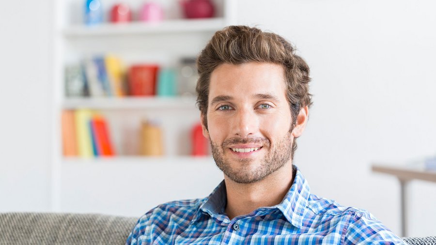 Усміхнений чоловік сидить у приміщенні