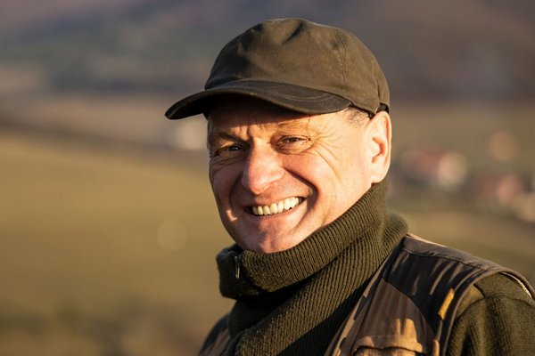 Чоловік посміхається на природі.