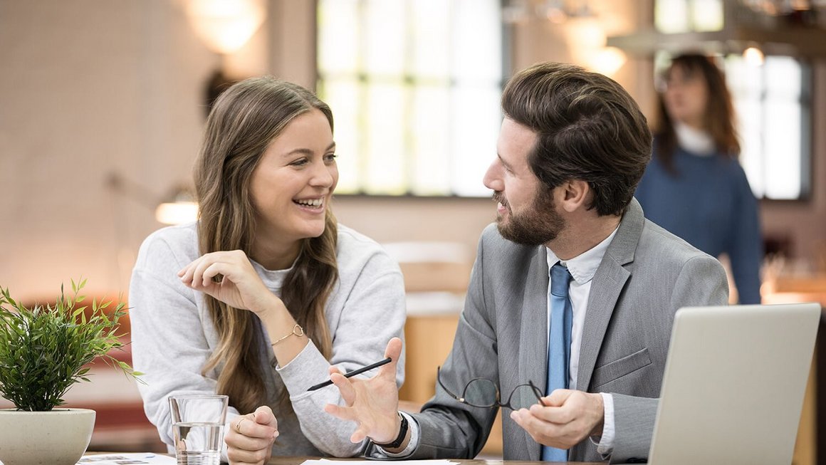 Чоловік і жінка розмовляють за столом у приміщенні