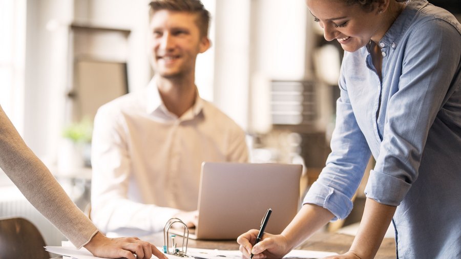 Люди працюють разом за столом та підписують документи.