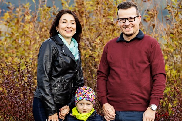 Сім’я з дитиною стоїть на вулиці та посміхається.