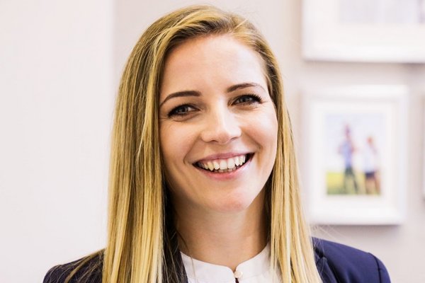 Жінка посміхається в діловому одязі.