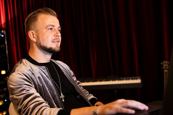 Чоловік працює за ноутбуком у студії звукозапису.