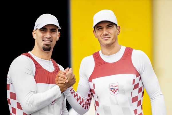 Двоє спортсменів тиснуть один одному руки та посміхаються.